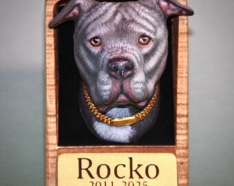 Puede incluir: Placa conmemorativa de madera con la cabeza esculpida de un perro gris y blanco con collar dorado. El nombre del perro, "Rocko", y los años "2011-2025" están grabados en una placa dorada en la parte inferior del marco.