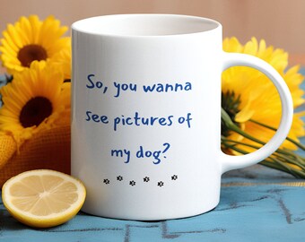May include: White ceramic mug with blue text that reads "So, you wanna see pictures of my dog?" with four black paw prints below the text.