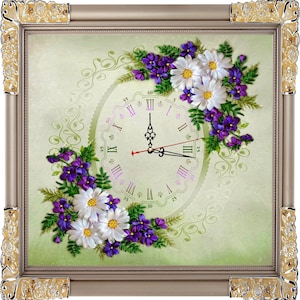 以下が含まれることがあります： 白い背景にリボン刺繍で花柄が施された、額縁に入った時計。時計の文字盤はローマ数字で、縁には繊細な花柄が描かれている。額縁は金色の装飾が施されている。