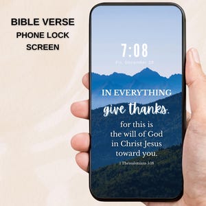 May include: A smartphone displaying a lock screen with a Bible verse. The screen shows a mountain landscape with the text "IN EVERYTHING give thanks." and the scripture reference 1 Thessalonians 5:18. The phone is held in a hand.
