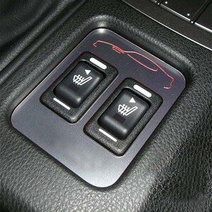 May include: A car interior panel with two black heated seat control switches. The switches have white indicator lines and a graphic of a seat with heat waves. A red car outline is on the panel.