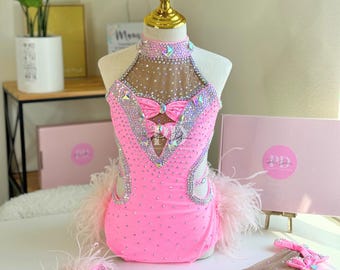 May include: Pink dance costume with a halter neckline, embellished with rhinestones and a bow. The costume features a sheer bodice and a pink skirt with a feathered trim.