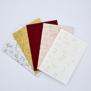 May include: Five laser cut invitation cards in different colors: silver, gold, burgundy, blush pink, and white. Each card features a delicate floral pattern.
