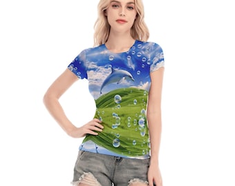 Op de afbeelding: Een t-shirt met korte mouwen voorzien van een levendige all-over print van een springende dolfijn tegen een helderblauwe lucht met witte wolken, boven een glooiend groen graslandschap, geaccentueerd met talloze zwevende bellen.
