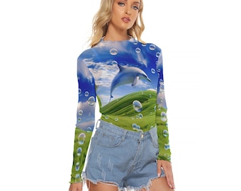 Op de afbeelding: Een shirt met lange mouwen met een blauwe, groene en witte print van een dolfijn die over een grasachtige heuvel met bubbels springt. Het shirt is gemaakt van een doorschijnende, gaasachtige stof.