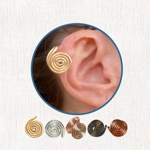 Photo of a person’s ear with a golden wire spiral cuff clipped onto the edge. Five wire spiral earcuffs are shown below in gold, silver, rose gold, dark bronze and dark copper colours.