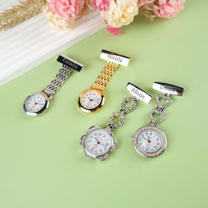 May include: Four silver and gold pocket watches with personalized name tags. The watches have a white face with black numbers and a red cross in the center. The watches are attached to a chain with a clip.