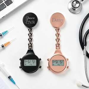 May include: Two digital fob watches with a chain link attachment. One watch is matte black with the engraved text Grace CNA, and the other is rose gold with the engraved text Daisy. Both feature a round digital display screen and side buttons.