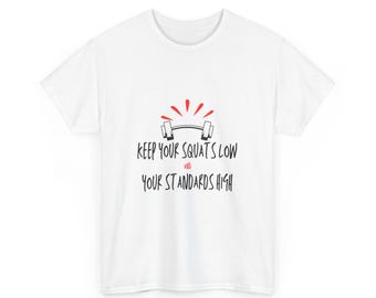 Peut inclure: T-shirt blanc avec l'inscription noire "KEEP YOUR SQUATS LOW AND YOUR STANDARDS HIGH", un dessin de barre et des accents rouges. Le t-shirt a un col rond et des manches courtes.