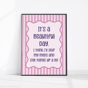 Könnte beinhalten: Gerahmter Kunstdruck mit rosa-weiß gestreiftem Hintergrund. Der Druck zeigt eine hellrosa, wellenförmige Form mit dem Text "It's a beautiful day. I think I'll skip my meds and stir things up a bit" in Lila.