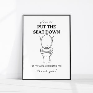 May include: Black and white printable sign with the text "Please put the seat down or my wife will blame me thank you!" and a cartoon illustration of a toilet with the lid up.
