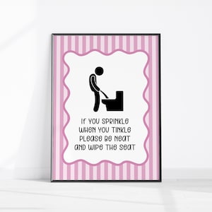 May include: Framed bathroom sign with a pink and white striped border and a decorative pink wavy inner border. The sign features a black stick figure and toilet graphic, with the text: "If you sprinkle when you tinkle please be neat and wipe the seat."
