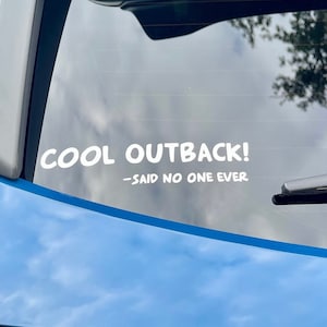 May include: A blue car with a white sticker on the back window that says "COOL OUTBACK! -SAID NO ONE EVER"