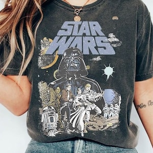 May include: A black t-shirt with a vintage-style Star Wars graphic. The graphic features Darth Vader, Luke Skywalker, Princess Leia, Chewbacca, R2-D2, and the text "Star Wars".