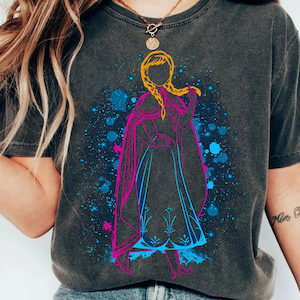 Könnte beinhalten: Ein dunkelgraues T-Shirt mit einer bunten Grafik eines Comic-Charakters mit langen blonden Haaren. Der Charakter trägt ein blaues und rosa Kleid und steht vor einem blauen und weißen Sternenhimmel.