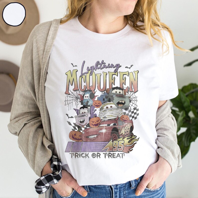 May include: White t-shirt featuring a Halloween-themed graphic with Lightning McQueen and other Cars characters dressed up. The design includes pumpkins, bats, and the text "Trick or Treat".