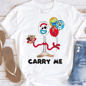 May include: White t-shirt with a cartoon image of Forky from Toy Story. Forky is holding a box of popcorn and a Mickey Mouse ear. He is wearing a red ribbon and the text "Carry Me" is printed below him.