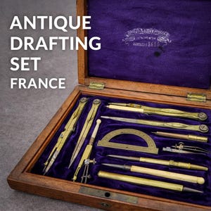 Könnte beinhalten: Antikes Zeichenset aus Frankreich, präsentiert in einer Holzkiste mit lila Samtfutter. Das Set enthält verschiedene Zeichenwerkzeuge aus Messing und elfenbeinfarbenem Material, wie Zirkel, Teiler und Lineale. Die Box hat goldfarbene Scharniere und den Text "Antique Drafting Set France".