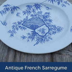 Peut inclure: Plat de service antique en faïence fine Sarreguemines 'Hrondunerrne Blue', 34x2 cm. Le plat présente un motif bleu et blanc de feuilles de bambou et d'oiseaux.