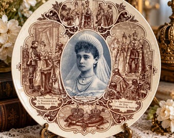 Könnte beinhalten: Ein runder dekorativer Keramikteller mit einem zentralen Porträt von Alexandra Feodorowna mit Schleier und Krone. Um das Porträt herum befinden sich braune Illustrationen königlicher Zeremonien mit französischem Text, darunter Le Clergé recevant le Tsar, Les Fiançailles du Tsarewitch et de la Princesse Alix und Le Couronnement du Tsar Cérémonie du Sacre.