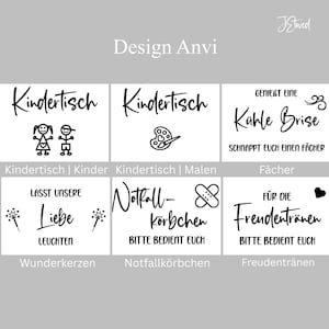 May include: A collection of six white rectangular signs with black text and graphics. The signs feature German phrases including Kindertisch, Genie&szlig;t eine k&uuml;hle Brise, Lasst unsere Liebe leuchten, Notfall-k&ouml;rbchen, and F&uuml;r die Freudentr&auml;nen, accompanied by icons like stick figures, a paint palette, sparklers, bandages, and a heart.