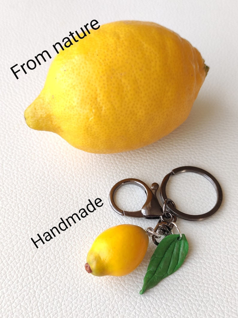 May include: A yellow lemon keychain with a green leaf charm. The keychain is handmade and says "From nature" and "Handmade".