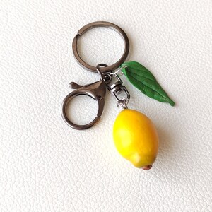 Handmade keychain featuring a realistic miniature lemon with a green leaf, attached to an antique dark -colored clasp. A charming and unique accessory for fruit lovers, adding a fresh and vibrant touch to keys or bags.