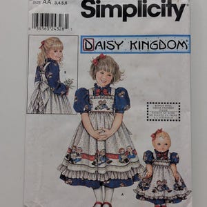 May include: Simplicity sewing pattern 9424 for a Daisy Kingdom dress in sizes AA 3, 4, 5, 6. The envelope features illustrations of a child and a doll wearing a blue and white dress with a Raggedy Ann and Andy print and red bows.