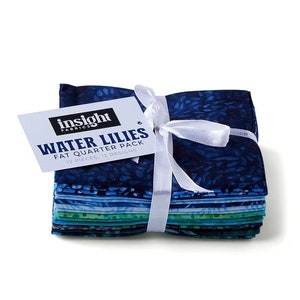 May include: A stack of 12 fat quarter fabric squares in blue and green hues with a white ribbon and a tag that reads "Insight Fabrics Water Lilies Fat Quarter Pack 12 Pieces, 12 Designs."