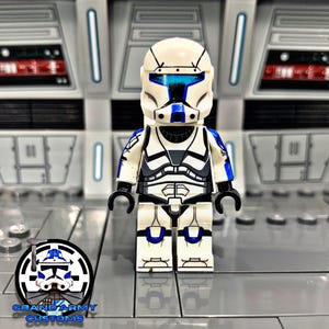 May include: A white and blue custom minifigure with black hands. The minifigure has a detailed helmet and armor design. The logo for Grand Army Customs is in the lower left corner. The background is a gray and white futuristic setting.