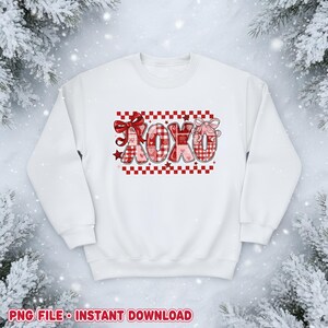 Peut inclure: Sweat-shirt blanc avec un motif XOXO rouge et rose. Les lettres sont dans un motif à carreaux avec des nœuds et des étoiles. Le motif est placé sur un fond à carreaux rouge et blanc. Le texte "PNG FILE • INSTANT DOWNLOAD" est en bas.