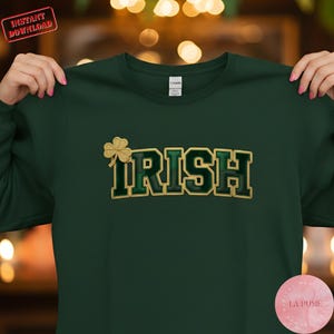 Peut inclure: Un sweat-shirt vert foncé avec le mot "IRISH" en lettres dorées et vertes de style universitaire. Un trèfle doré est placé à gauche du mot. Le sweat-shirt est de la marque Gildan. Le texte "Instant Download" est dans un encadré rouge en haut à gauche.