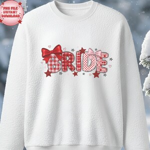 Puede incluir: Sudadera de forro polar blanca con la palabra "BRIDE" en letras rojas y rosas. Las letras tienen una mezcla de patrones, incluyendo cuadros y lunares. Lazos y estrellas rojos y rosas decoran el diseño.