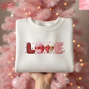 Peut inclure: Sweat-shirt blanc avec le mot "LOVE" décoratif. Le "L" est rouge, le "O" rose avec un nœud rouge, le "V" blanc avec un ours en peluche et le "E" à carreaux rouges et blancs. Tampon "Téléchargement instantané".