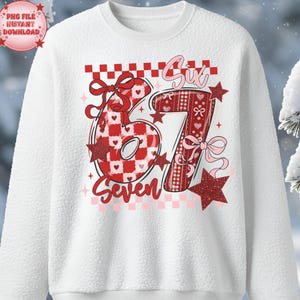 Peut inclure: Sweat-shirt blanc avec un motif à carreaux rouges et blancs représentant les chiffres "67" et le mot "Seven". Les chiffres sont décorés de cœurs, de nœuds et d'étoiles. Le mot "Six" est écrit au-dessus du chiffre 6.
