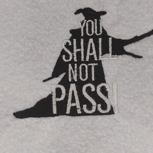 May include: Black silhouette of a wizard with a pointed hat and staff, with the text "You Shall Not Pass" in white.