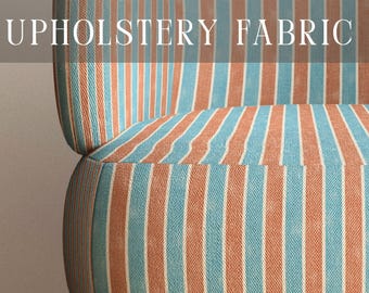 May include: A piece of furniture upholstered in a fabric featuring vertical stripes in alternating shades of light blue and muted orange. The text PREMIUM UPHOLSTERY FABRIC is displayed at the top, and APOSTROFO DESIGN is at the bottom.