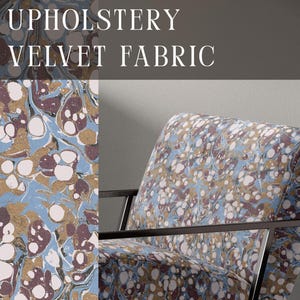 May include: Upholstery velvet fabric featuring a marbled pattern in shades of light blue, dark maroon, white, and gold. The fabric is displayed on an armchair with a black metal frame. The text UPHOLSTERY VELVET FABRIC and APOSTROFO DESIGN are visible.
