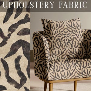 May include: An armchair upholstered in a beige fabric with a dark brown abstract animal-like print. The chair features a square back cushion and a seat cushion with the same pattern. The text DESIGNER UPHOLSTERY FABRIC and APOSTROFO DESIGN appear.