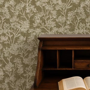 May include: A dark wooden desk with open compartments and a drawer, with an open book on top. The desk is in front of a wall with a floral pattern in shades of green and white. The text "APOSTROFO DESIGN" is at the bottom.