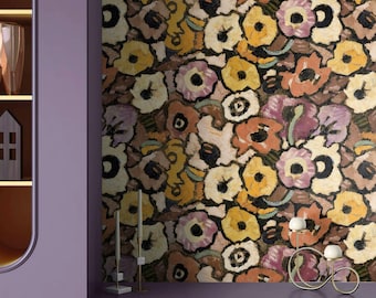 May include: Wallpaper featuring a dense, painterly floral pattern in shades of yellow, mauve, orange, and black. The design is displayed on a wall behind a purple shelf with two thin candle holders and a curved metal candle holder. APOSTROFO DESIGN.