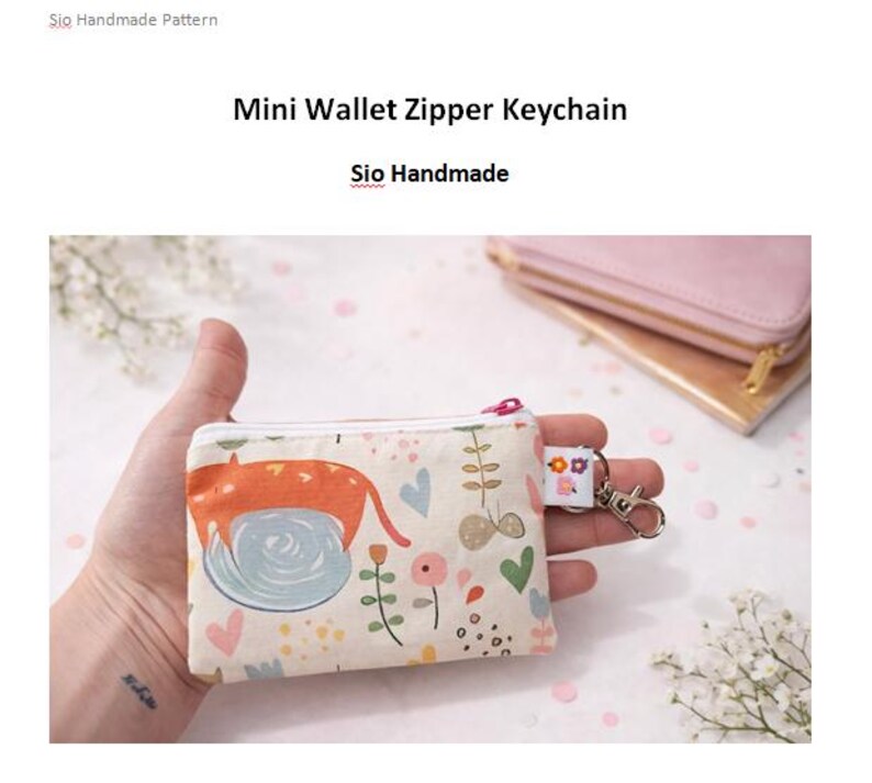 K&ouml;nnte beinhalten: Ein kleines, beiges Mini-Geldb&ouml;rsen-Rei&szlig;verschluss-Schl&uuml;sselanh&auml;nger mit einem bunten Katzen- und Blumenmuster. Die Geldb&ouml;rse hat einen Rei&szlig;verschluss und einen silberfarbenen Schl&uuml;sselanh&auml;nger-Clip. Der Text "Mini Wallet Zipper Keychain" und "Sio Handmade" sind sichtbar.