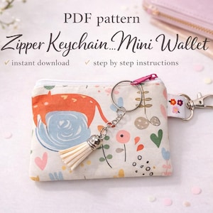 May include: A patterned mini wallet with a zip and keychain. The design includes an orange fox, blue water, and floral details. The text "Zipper Keychain...Mini Wallet" is visible. The wallet is a PDF pattern.