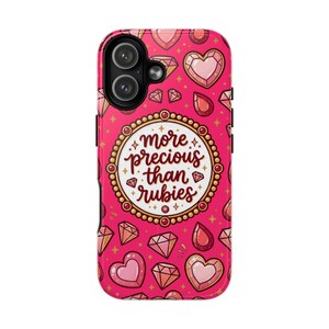 May include: A pink phone case with a repeating pattern of diamonds, hearts, and gemstones. The center features a gold-bordered circle with the text "more precious than rubies" in a script font. The case has a black border and camera cutouts.
