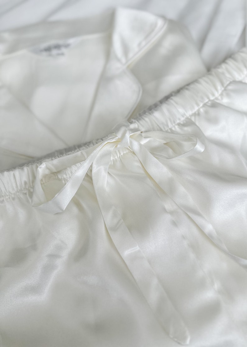 Puede incluir: Pantal&oacute;n de pijama de sat&eacute;n blanco con cintura el&aacute;stica y un lazo de cinta de sat&eacute;n.