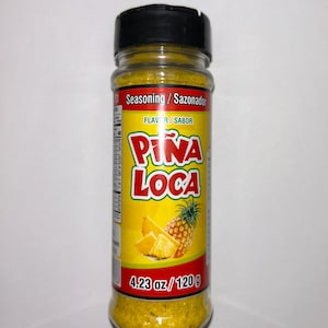 May include: A clear plastic bottle of yellow seasoning with a black cap. The label reads "Pi&ntilde;a Loca" with a pineapple illustration. The bottle contains 120 g of seasoning.