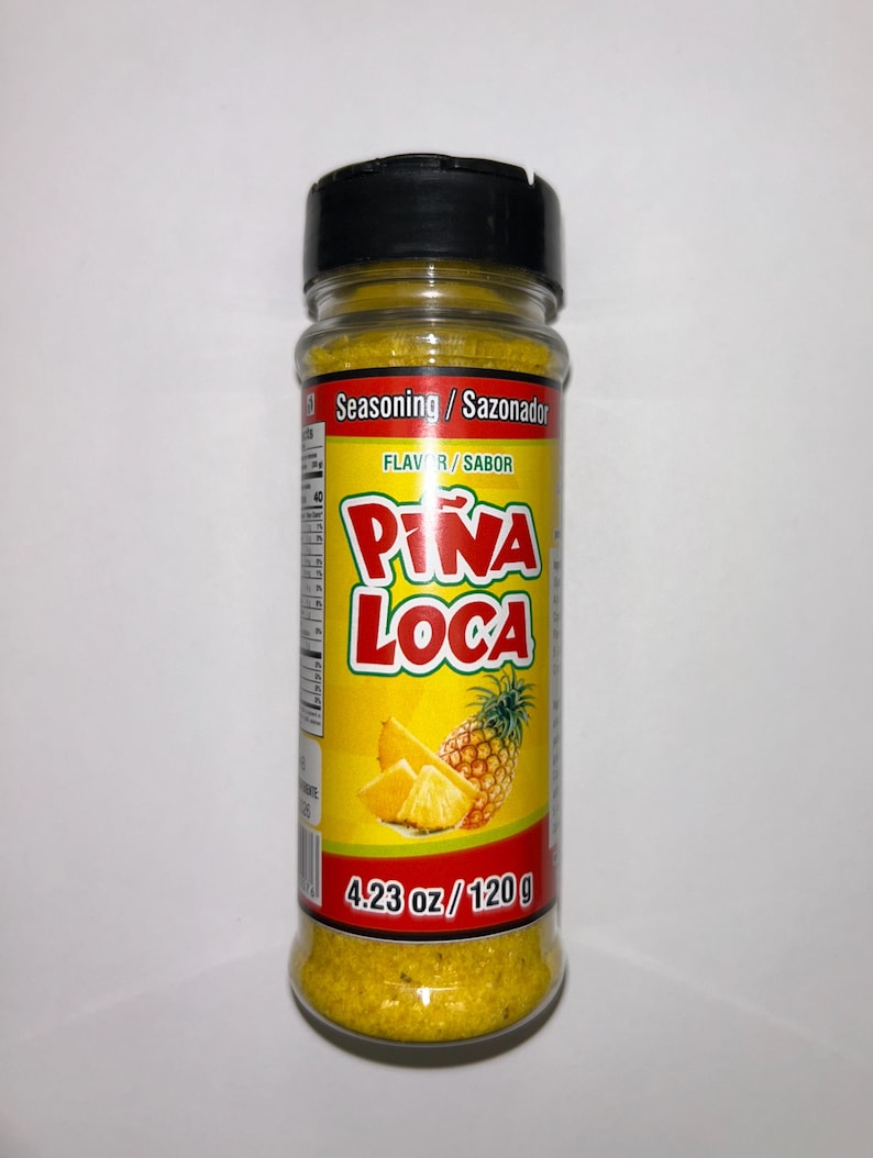 May include: A clear plastic bottle of yellow seasoning with a black cap. The label reads "Pi&ntilde;a Loca" with a pineapple illustration. The bottle contains 120 g of seasoning.