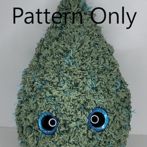 May include: A plush, green, teardrop-shaped creature with large, glittery blue eyes. The soft, textured body is accented with blue thread. The words "Pattern Only" are printed in black across the top.
