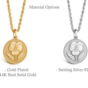 May include: Two necklaces with rope chains and circular pendants featuring a pansy flower design. One pendant is gold-colored with text reading Material Options, Gold Plated, and 14K Real Solid Gold. The other is silver-colored with text reading Sterling Silver 925.