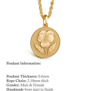 May include: A gold-toned necklace featuring a round pendant with a raised pansy flower design and a beaded border. The pendant has a thickness of 0.6mm and hangs from a rope chain that measures 2.10mm in thickness. The metal surface has a matte finish.
